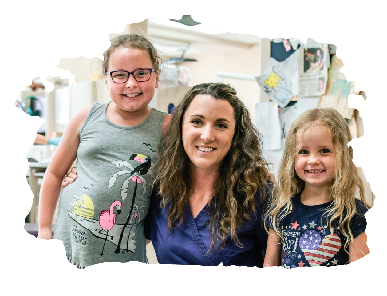A dental assistant poses with two young smiling patients.